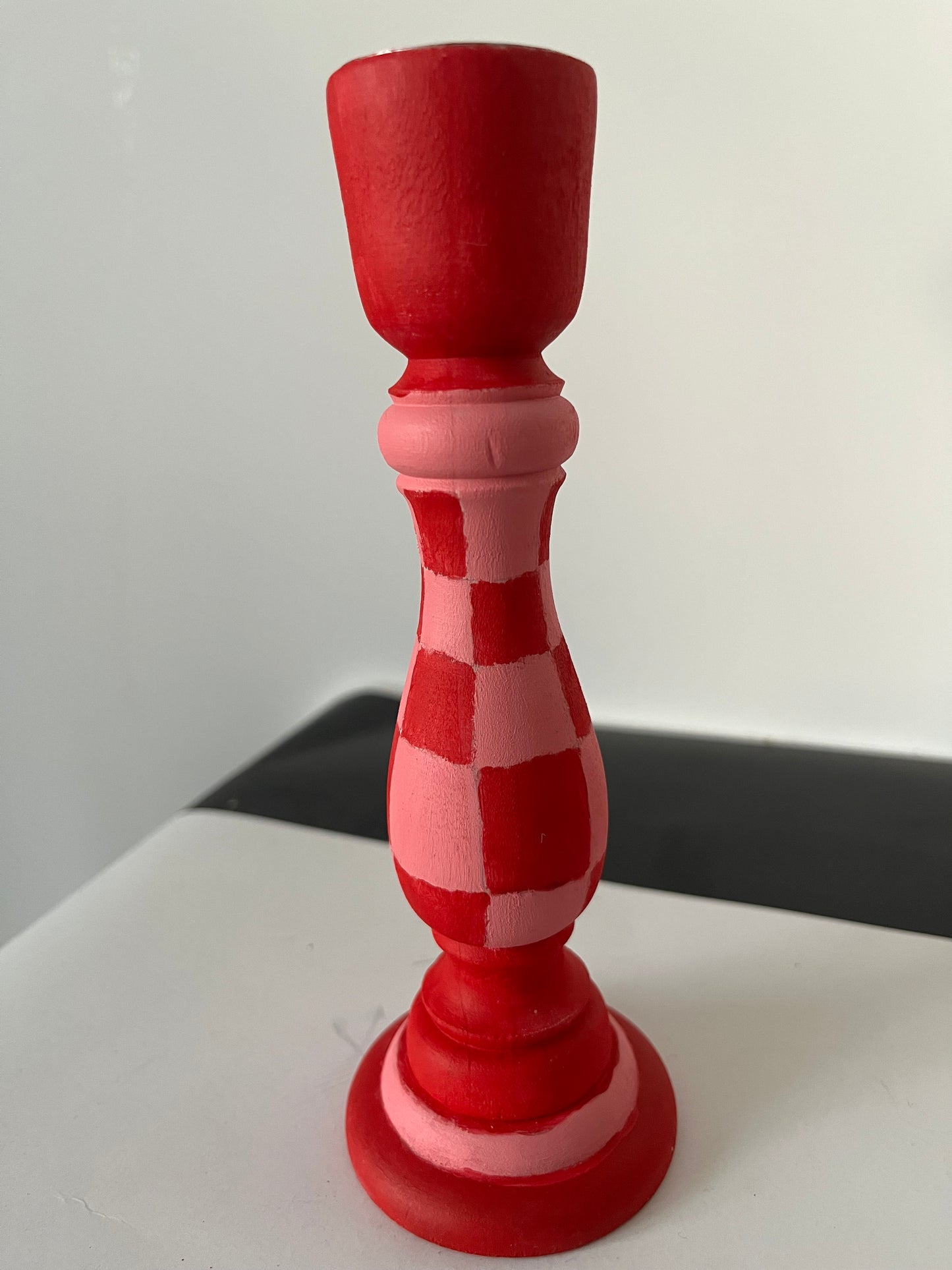 Red and white checkered candlestick on a light gray background